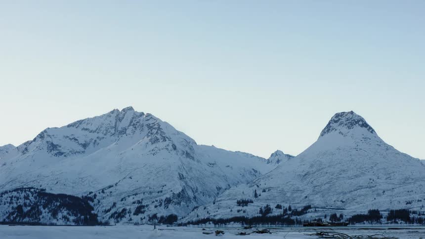 The tall mountain is covered with snow on a sunny day