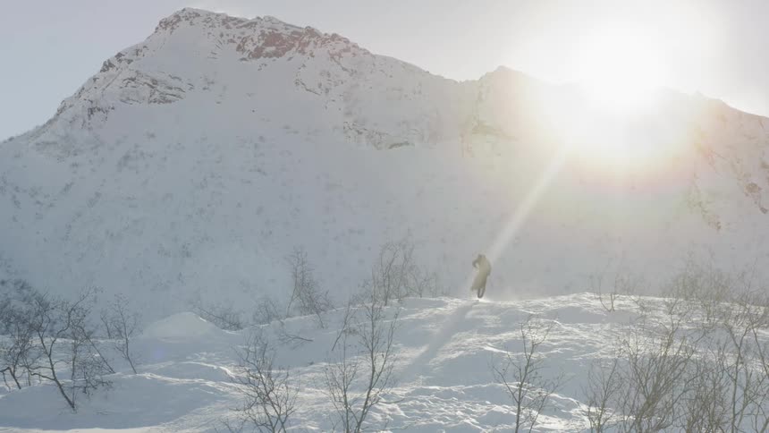 A bicyclist rides down a snowy mountainside at sunset