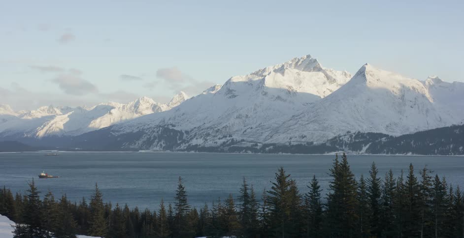 The sun shines on snow capped coastal mountains