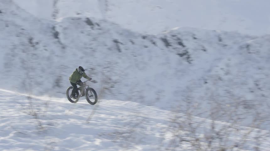 A person is jumping over hills on a bike in the snow