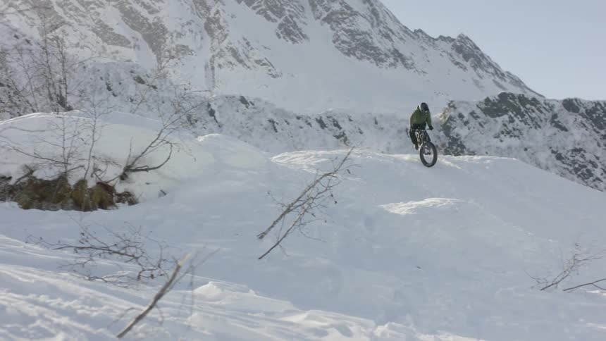 A person is riding a mountain bike down a snow-covered hillside