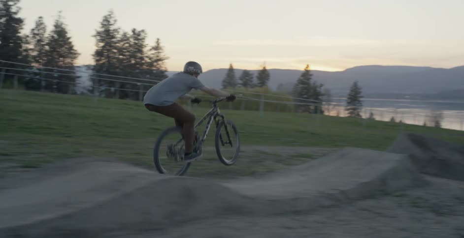 The man does a pop wheelie while riding his mountain bike