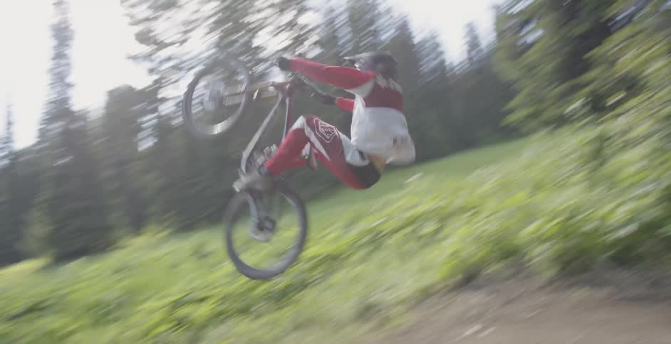 A bmx rider performs a flip off of a dirt ramp
