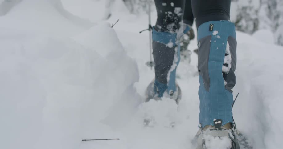 People in snow shows make their way through the snow