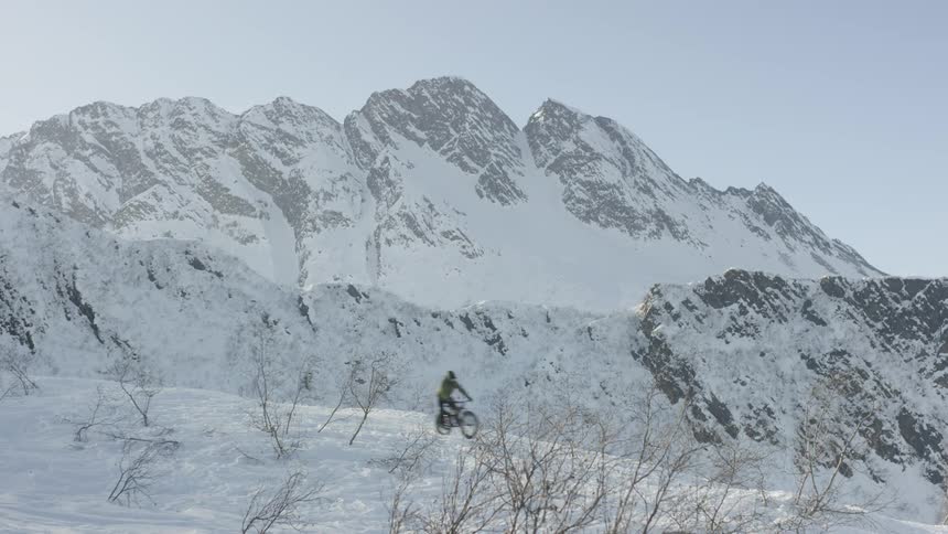 A person drives downhill in the snow on a bicycle
