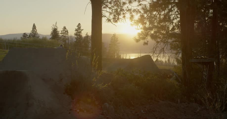 A bicyclist goes over a jump at sunset