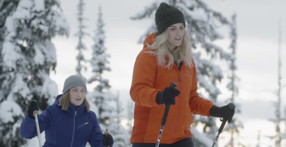 Two women are hiking up a hill on a winter's day