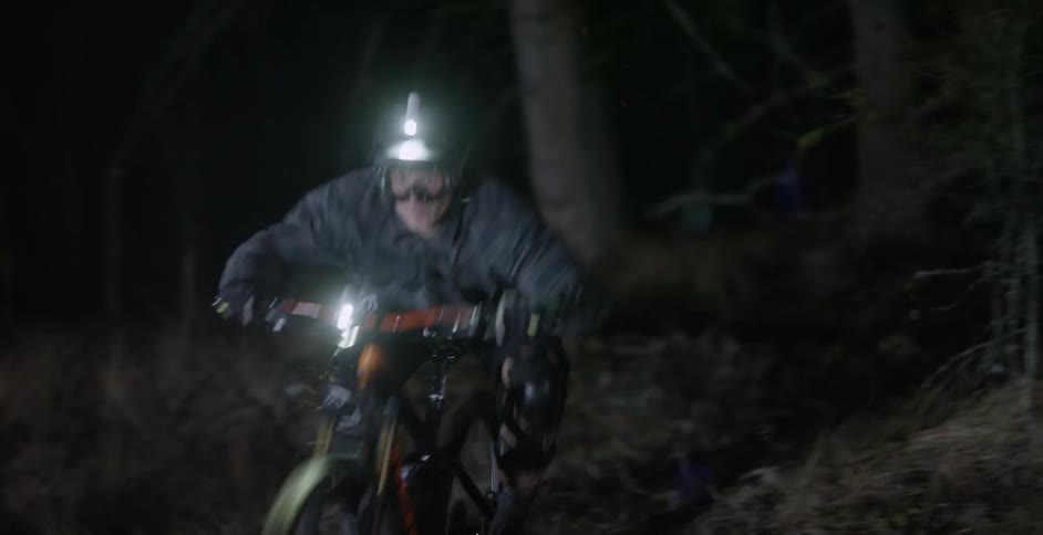 A person is riding a mountain bike down a path in a natural setting at night