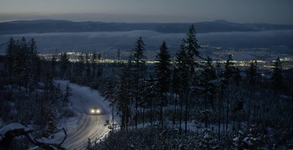 A car drives down a snowy mountain road
