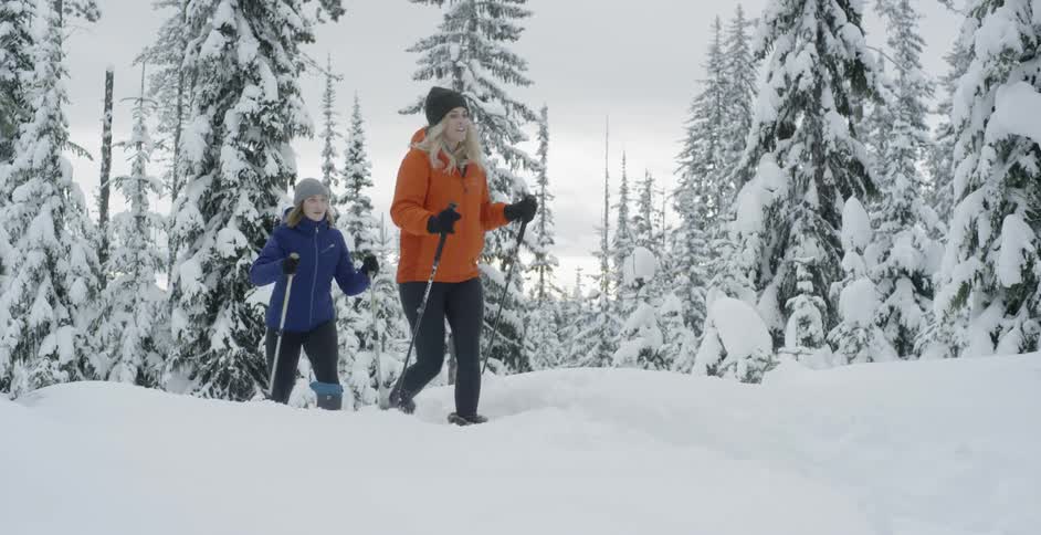 Two women hike up a snowy hill