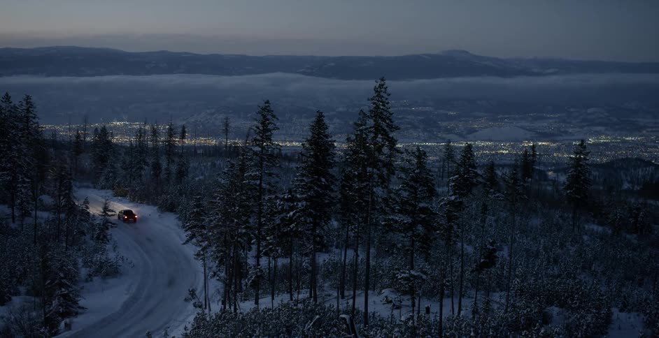 A pickup truck travels on a snow covered road