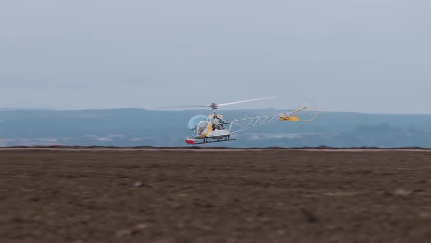 A helicopter flies over the long field