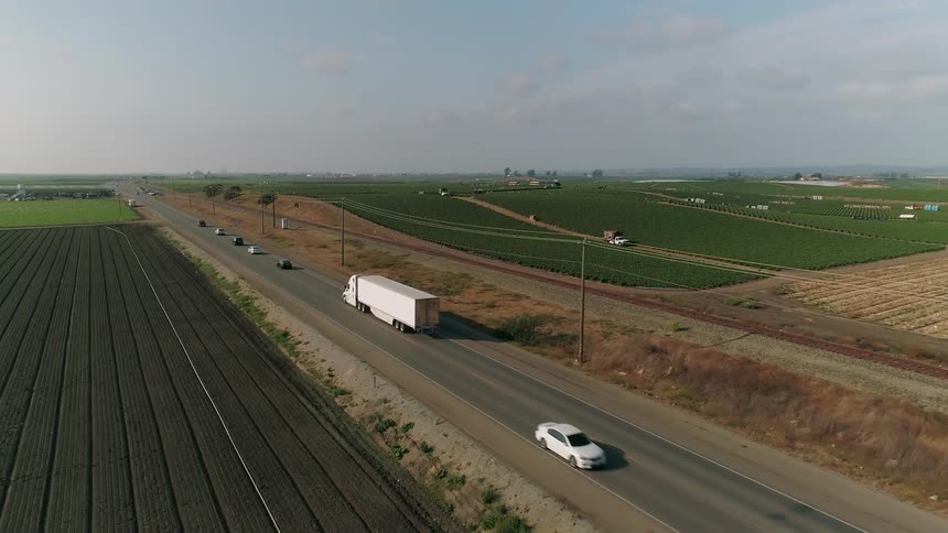 Cars drive along the road by the farms