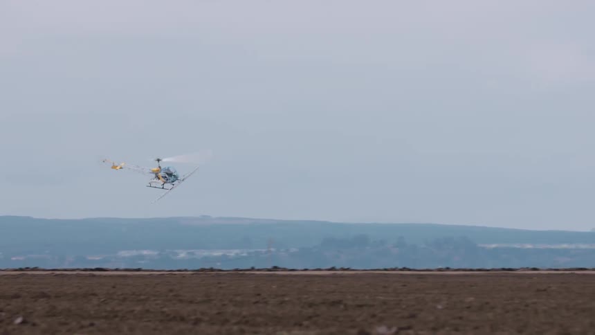 A helicopter is dusting crops as it flies above a farm field during the day
