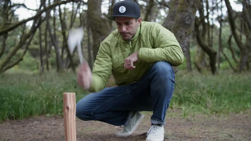 Man chops a small piece of wood with a hatchet