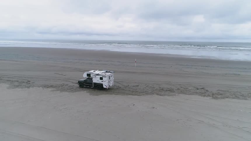 The recreational vehicle drives on the beach on a cloudy day