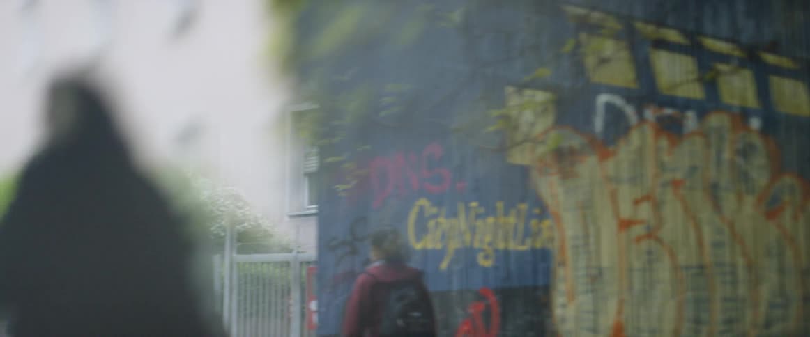 People walk past a wall covered in graffiti