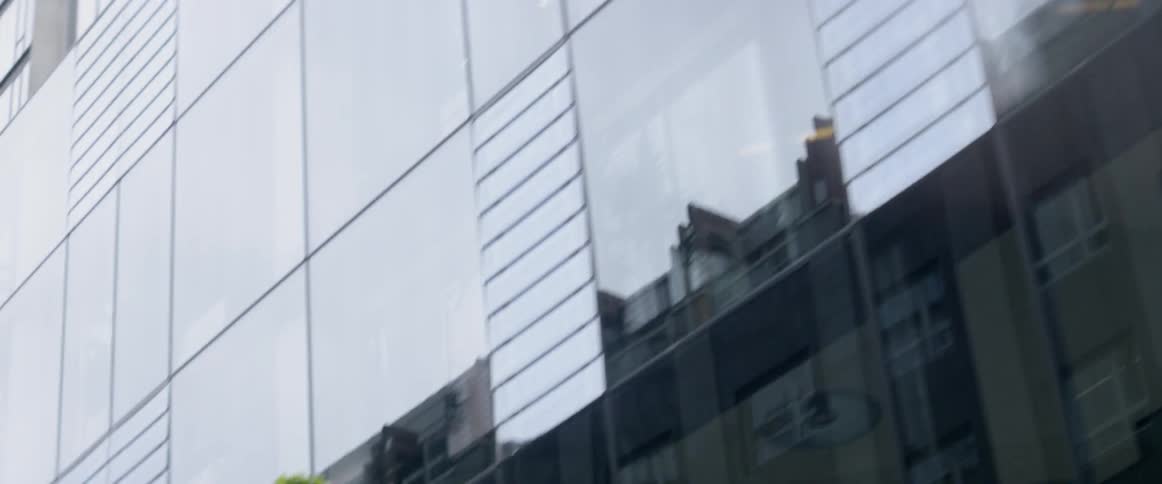 A car drives by a glass city building