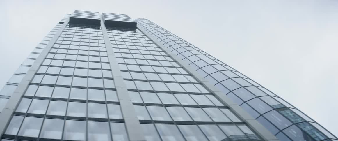 The windows of a skyscraper reflect the sky and the surrounding buildings