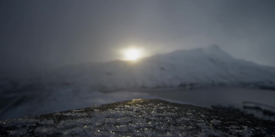 The sun is setting beyond snow-covered mountains