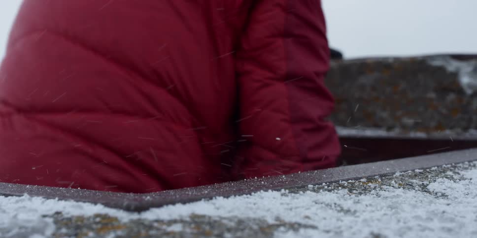 A man walks out of a concrete lookout building in the snow