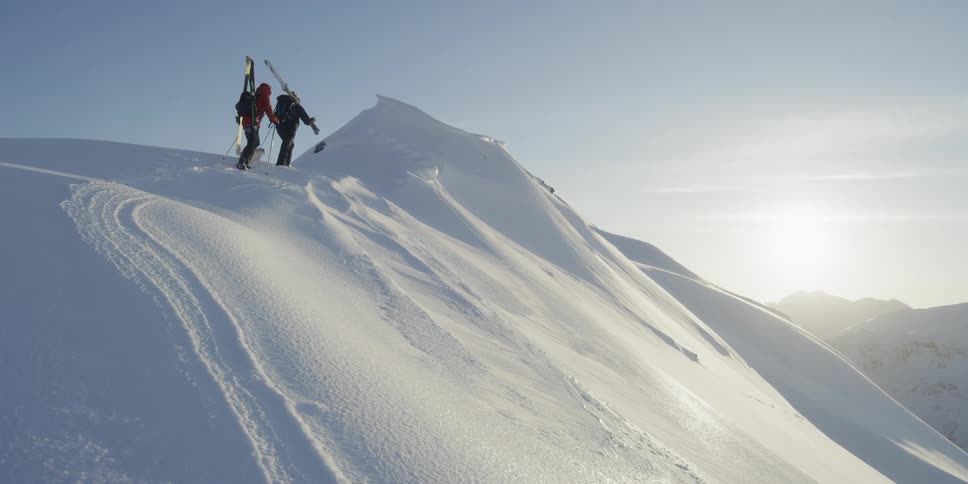 Two skiers hike a snowy ridge