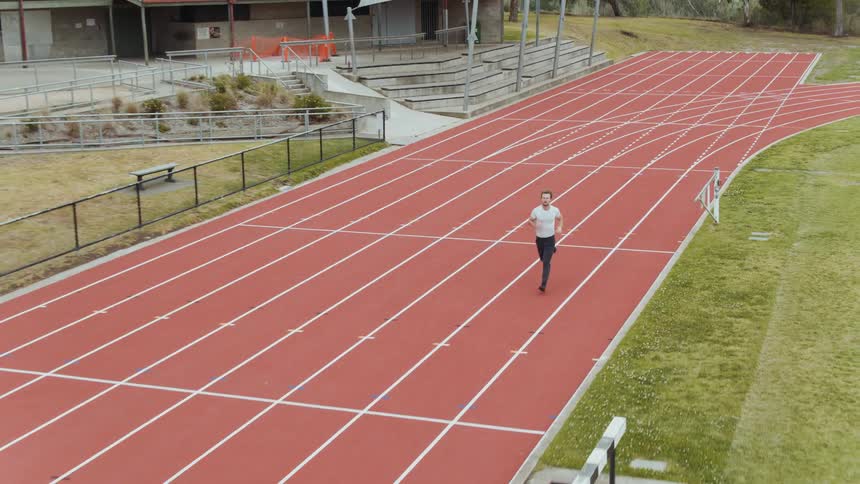A man is jogging on a track during the day