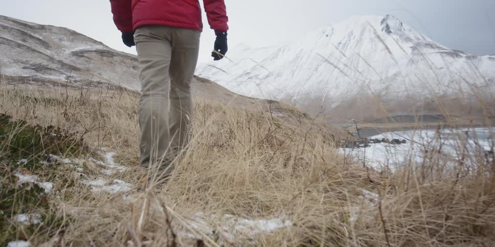 A man is walking on a coastal ridge line on a cold day