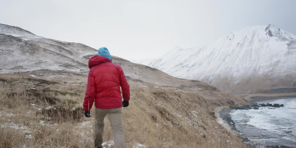 A hiker walks above the shore in winter