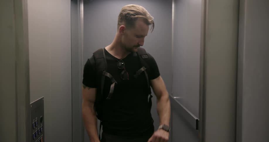 A man is getting into an elevator and checking his watch