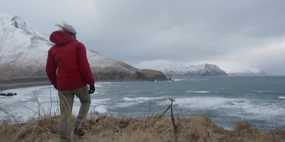 A man walks toward the water on a windy day