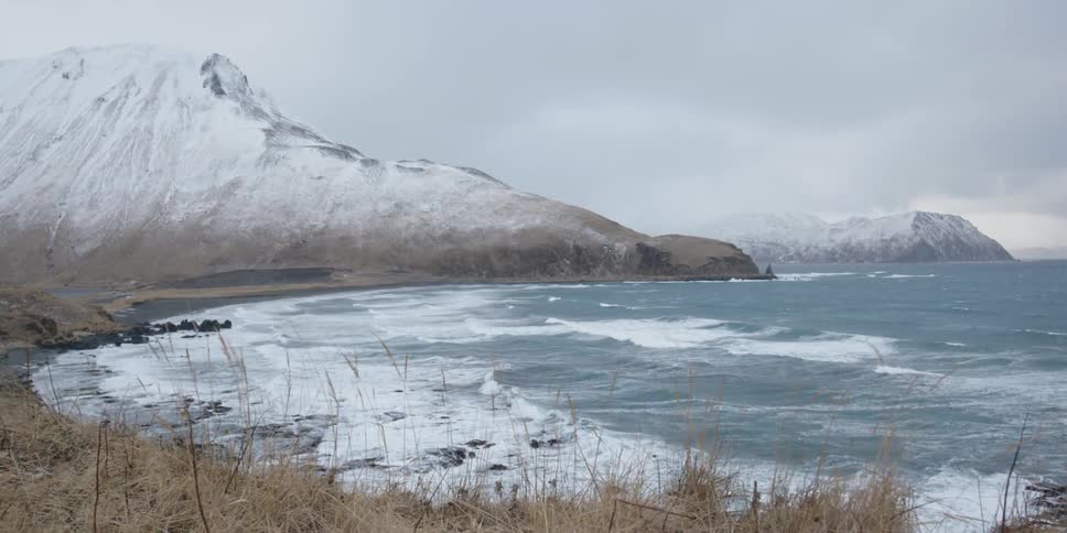 The waves crash against the snowy shore