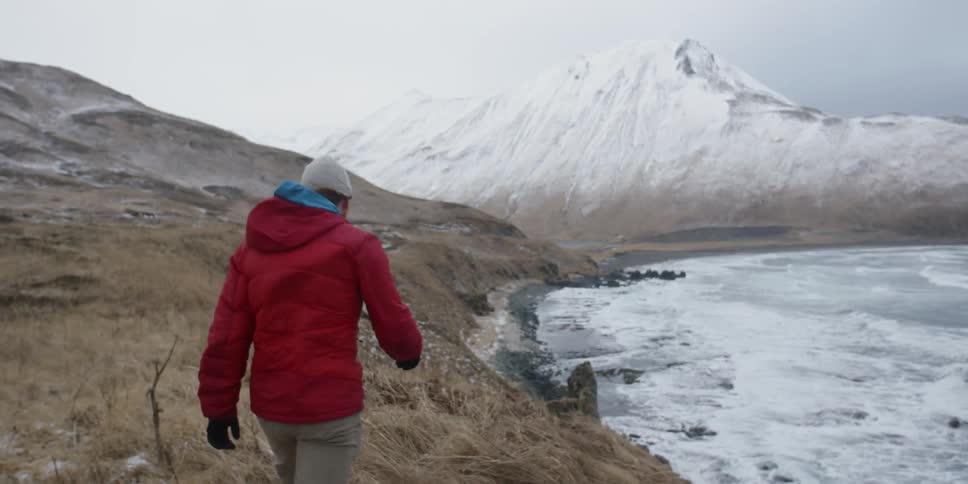 A man is walking on a coastal ridge line on a cold day
