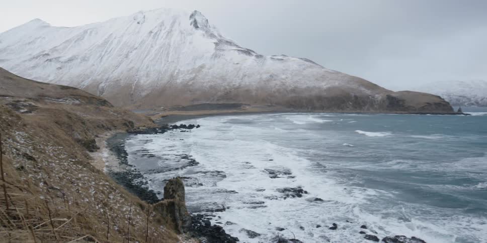 Waves are crashing against rocks on a stormy winter's day