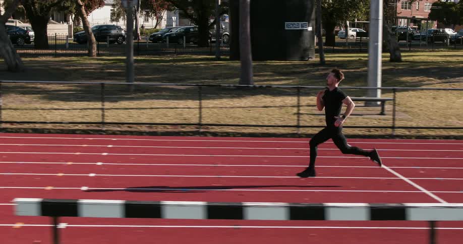 A man is jogging on a track during the day