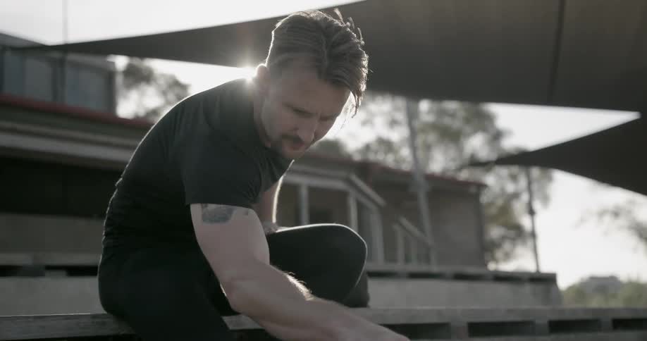 A man stretches on outdoor bleachers