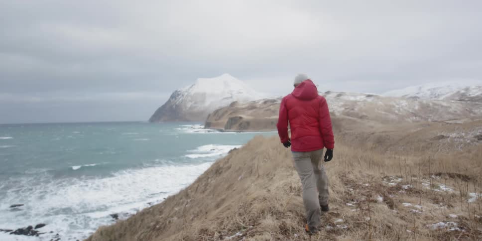 A man is hiking on a coastal ridge on a cold and windy day