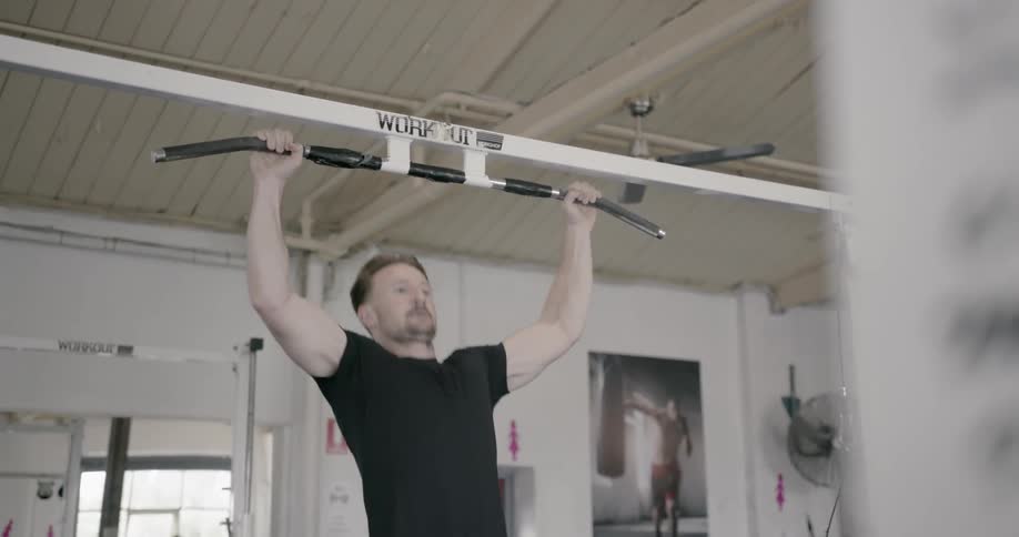 A man is doing pull ups in the gym