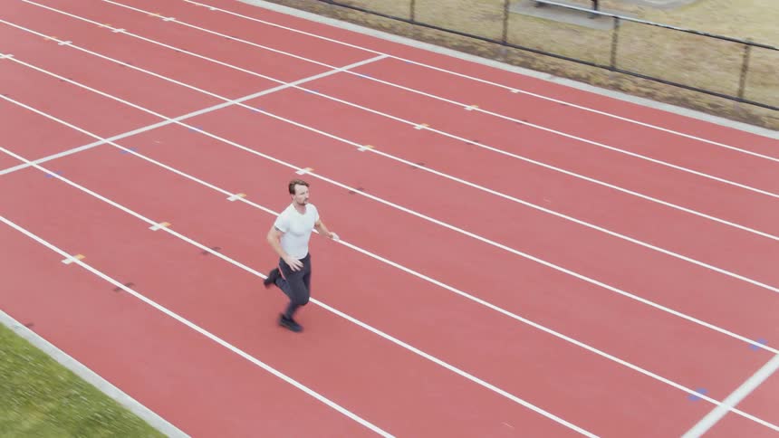 A man is jogging on a track during the day