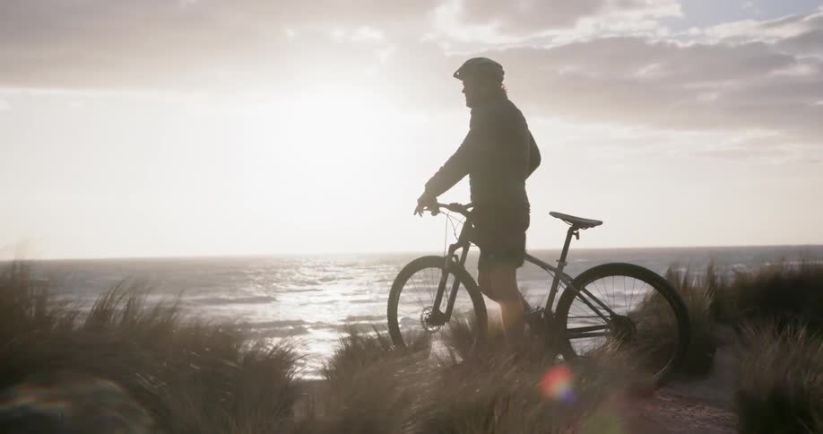 A man rides his bike by the shore on a windy day