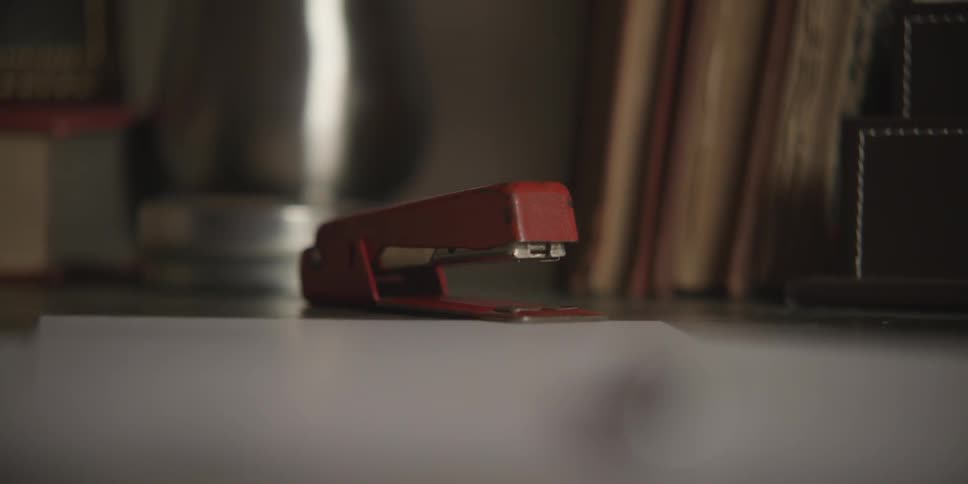 A red stapler sits on a desk