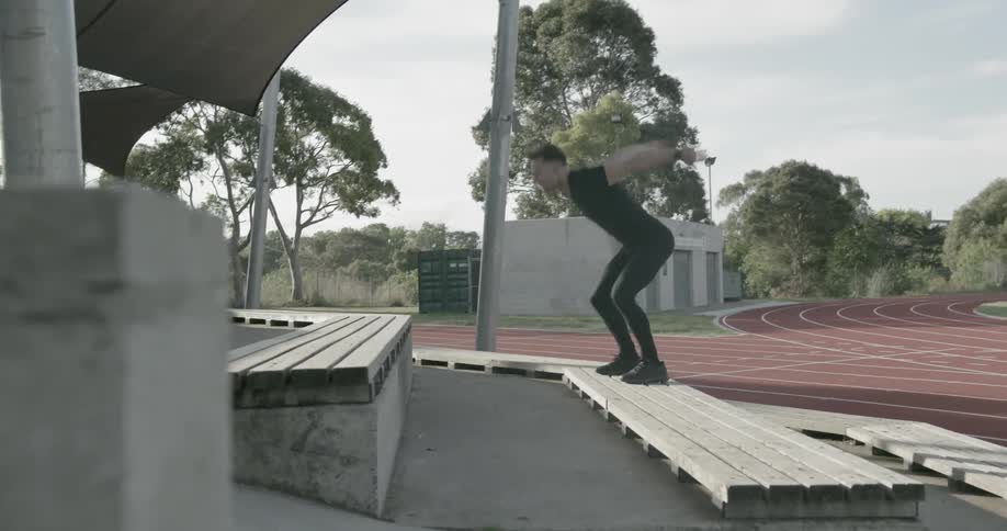A man jumps up steps next to a running track