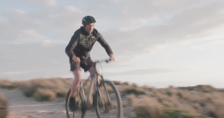 A bicyclist rides along a coast at sunset