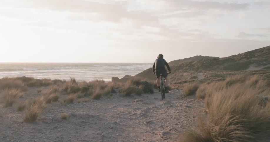A man rides a mountain bike on a trail near the ocean