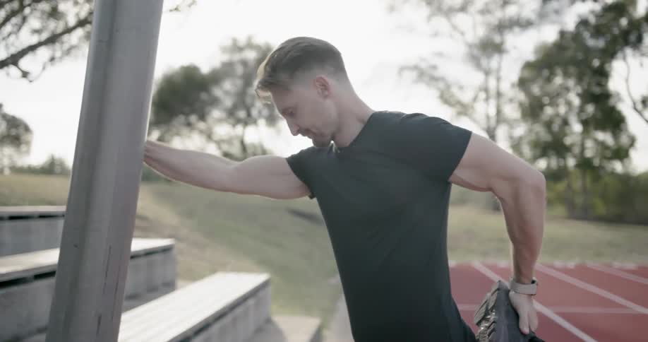 A man stretches next to an outdoor track