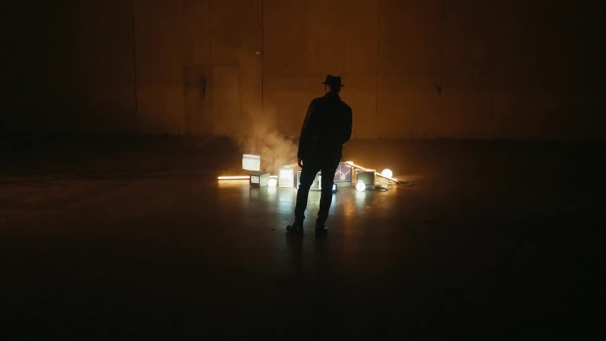 A man shines a flashlight on a stack of monitors on the ground