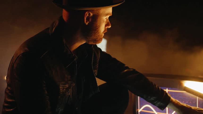 A man is touching a television sitting on the ground in a dark room