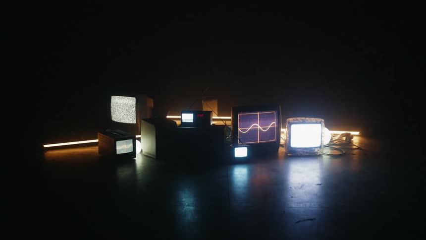 Various television monitors are displaying static and flickering images