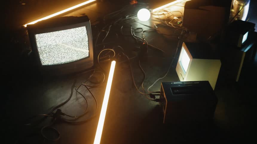 Various television monitors are displaying static and flickering images
