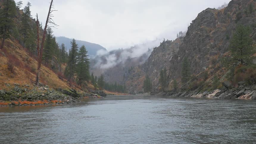 A river flows between hills on a cloudy day
